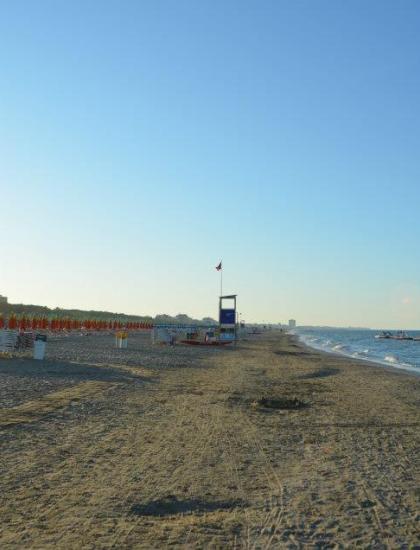 Beach at sunset with closed umbrellas and calm sea.