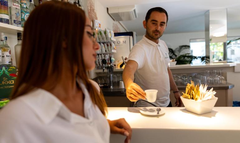 Barista serviert Kaffee an eine Kundin am Tresen.
